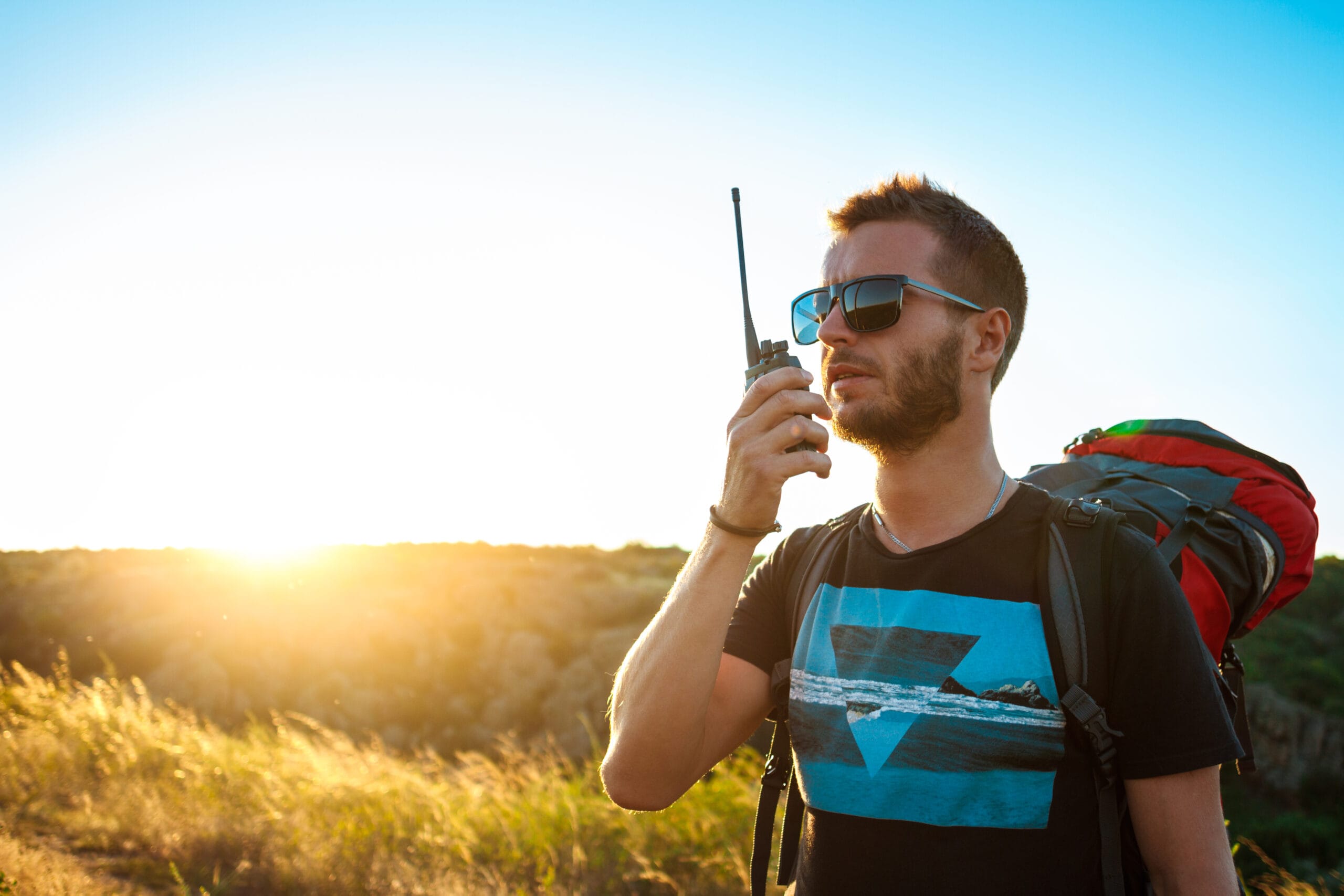 Young handsome man talking on walkie talkie radio, enjoying canyon view.